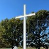 picture of a cross in front of trees and a pond